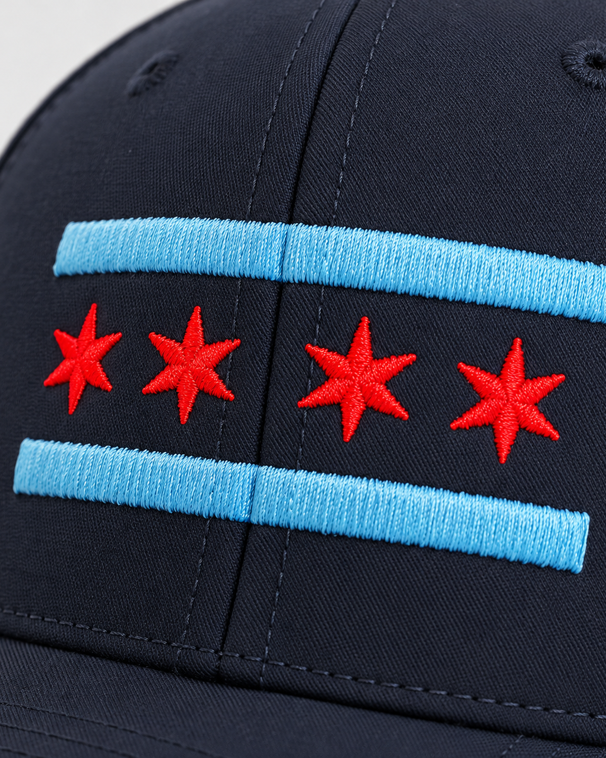 Close-up of the embroidered Chicago flag: light blue stripes and four red six-pointed stars