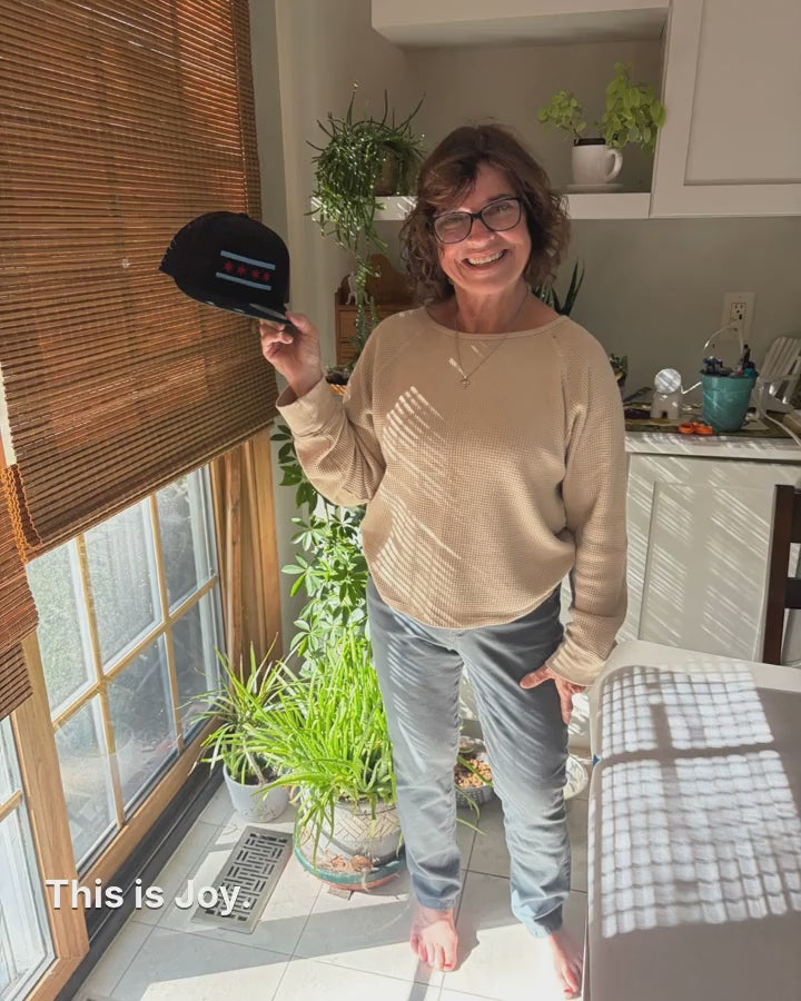 Joy holding a Chicago flag hat, Joy at her embroidery machine, a Chicago flag being stitched onto a cap, and Tim riding orders to the post office on his e-bike